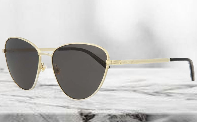 Gucci Goldtone Dark Gray Cat Eye Sunglasses on a Table Gucci Goldtone Dark Gray Cat Eye Sunglasses on a Table