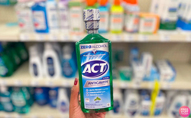 Hand Holding Act Anticavity Mouthwash 18 Ounce Bottle in Front of the CVS Shelf