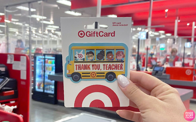 Hand Holding Teacher Gift Card in front of Registers at Target