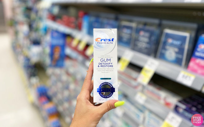 Hand Holding a Crest Pro Health Gum Detoxify Restire Toothpaste Hand Holding a Crest Pro Health Gum Detoxify Restire Toothpaste