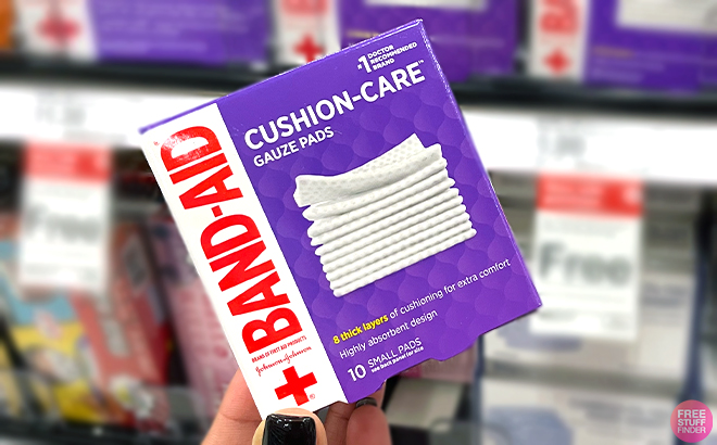 Hand holding one Band Aid Brand Cushion Care Gauze Pads 10 Count