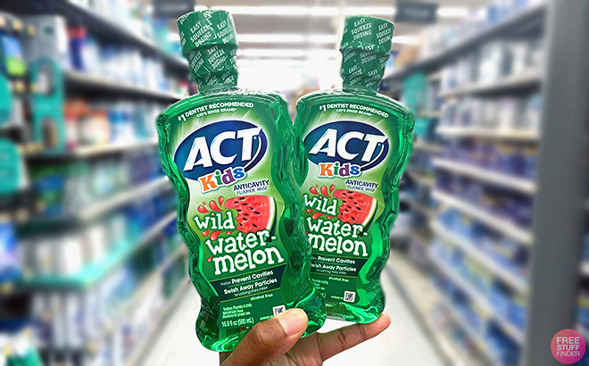 Hand holding two ACT Kids Anticavity Fluoride Rinse Wild Watermelon 16 9 Ounce