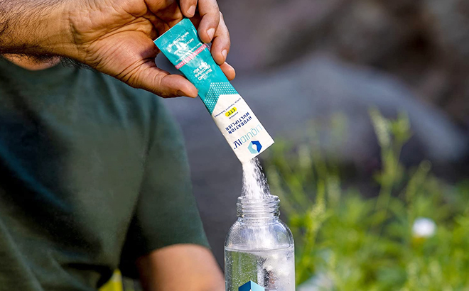 Man Pouring Liquid I V Hydration Multiplier with Strawberry Lemonade Flavor into a Glass Bottle
