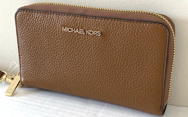 Michael Kors Large Pebbled Leather Smartphone Wristlet Against a White Wall