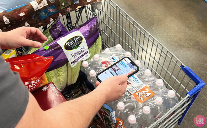 Man Holding a Phone Scanning Products Inside a Shopping Cart in a Sam's Club Store