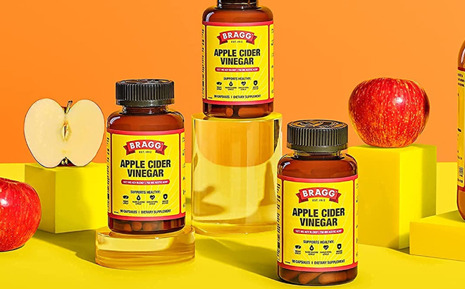Three Bottles of Bragg 90 Count Apple Cider Vinegar Capsules 750mg with Apples on the Sides Three Bottles of Bragg 90 Count Apple Cider Vinegar Capsules 750mg with Apples on the Sides