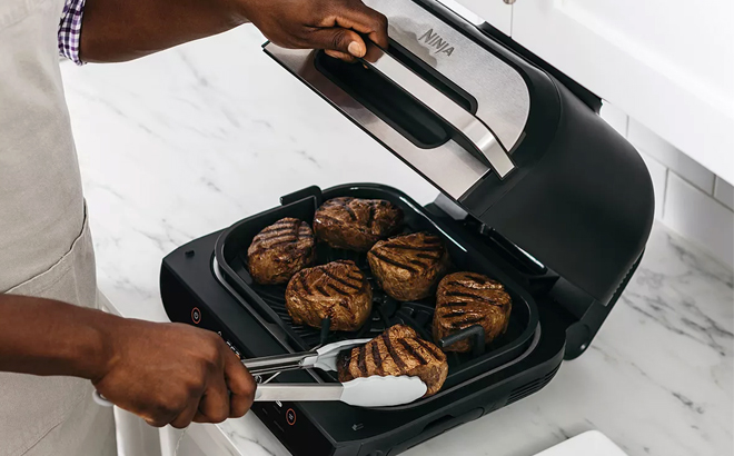 Woman Cooking Meat on the Ninja Foodi 6 in 1 Smart XL Indoor Grill and Air Fryer Woman Cooking Meat on the Ninja Foodi 6 in 1 Smart XL Indoor Grill and Air Fryer