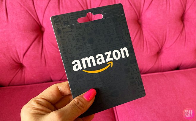 Hand Holding Amazon Gift Card in front of a Pink Couch