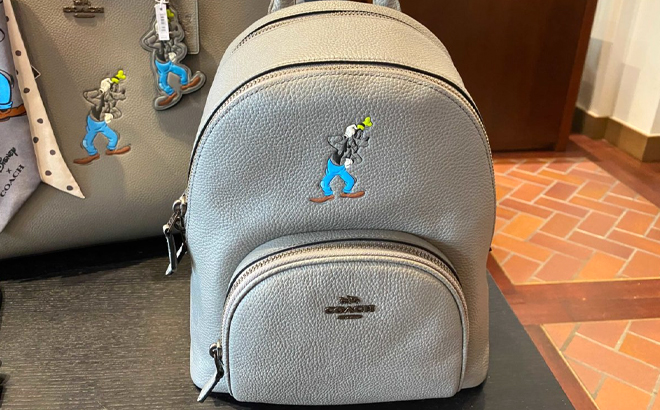 Disney X Coach Carrie Backpack 23 With Goofy Motif on a Table