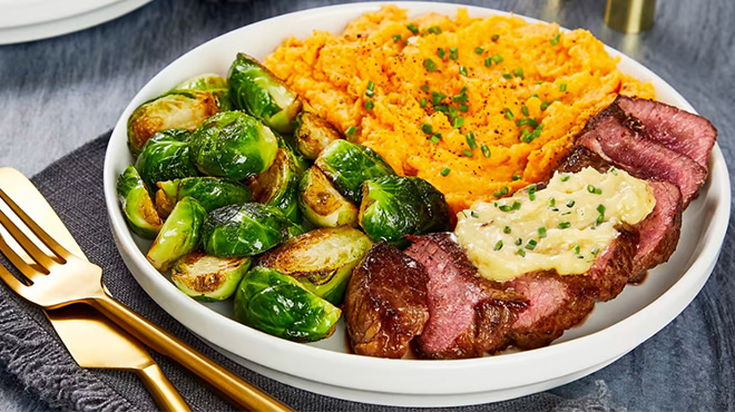 A Plate with Steak, Brussels Sprouts and Mashed Potatoes on It Next to Gold Cutlery
