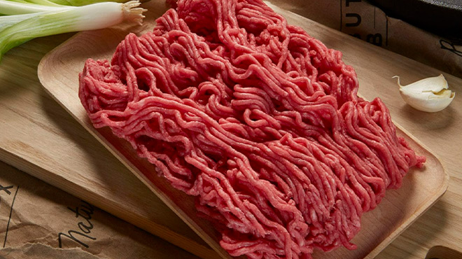 Ground Beef in a Wooden Plate on top of a Cutting Board on a Kitchen Countertop