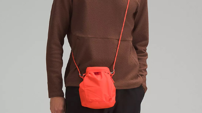 Man Wearing Lululemon Roll Top Crossbody Bag in Solar Orange White Opal Color