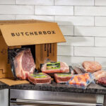 Opened ButcherBox with Meat Pieces Falling Out on a Kitchen Counter