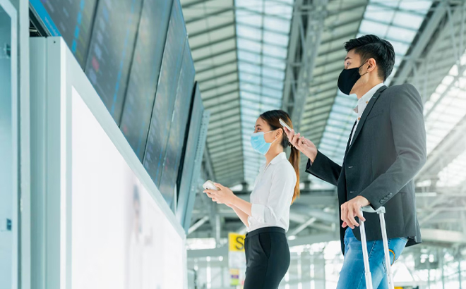 People in Face Masks Checking Flight Schedules