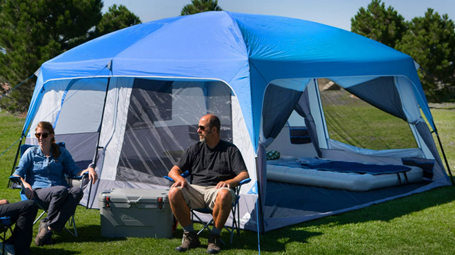 Three People Sitting Beside Ozark Trail Hazel Creek 14 Person Camping Cabin Tent
