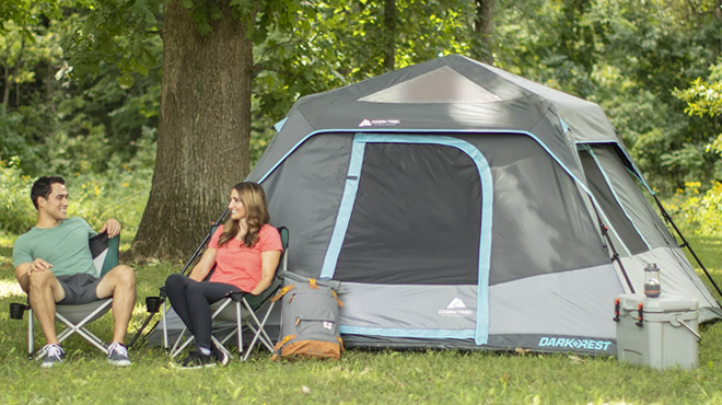 Two People Sitting Beside on Folding Chairs Beside Ozark Trail 6 Person Dark Rest Instant Cabin Tent