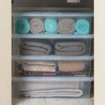 Four Mainstays 28 Quart Plastic Storage Boxes with Towels and Linens Inside a Closet