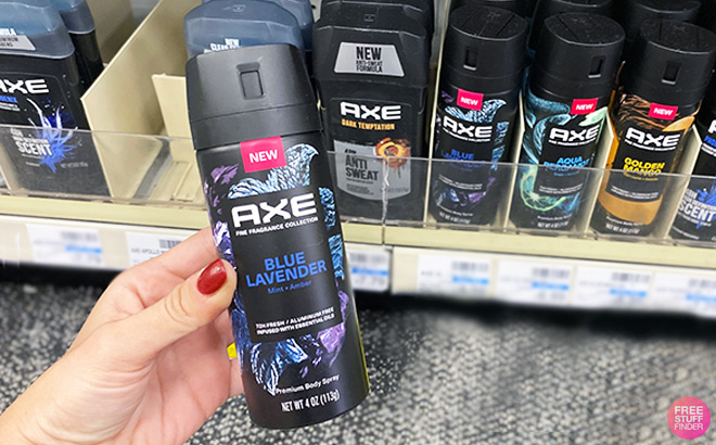 Hand Holding Blue Lavander Axe Fragrance in front of Shelves In Store