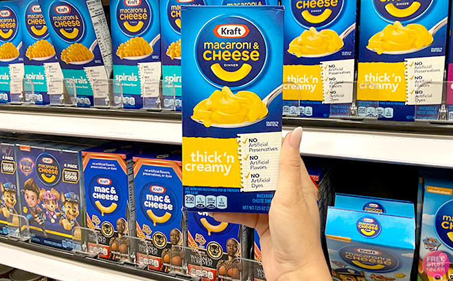 A Hand Holding Kraft Macaroni and Cheese Thick'n Creamy Dinner in a Store Aisle