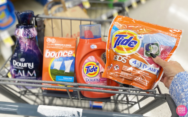 Hand Holding Tide Pods with Other Laundry Care Products in Cart