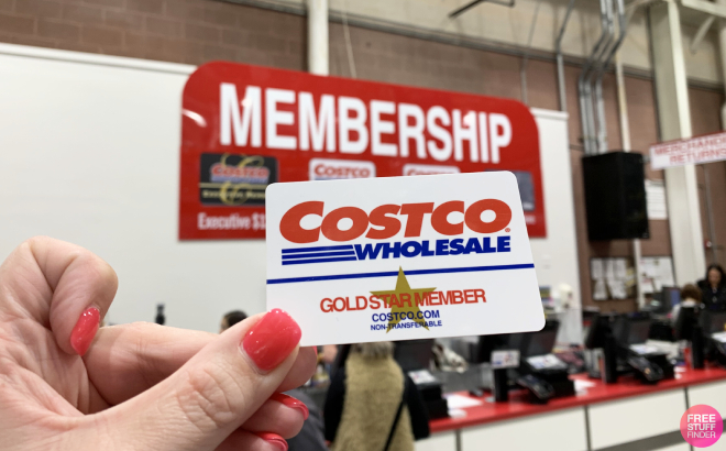 Hand Holding a Costco Gold Star Membership Card in Front of the Membership Booth