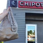 Person Holding Chipotle Bag in front of Chipotle Store