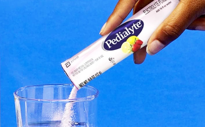 Woman Pouring Pedialyte Electrolyte Powder Packet on a Glass