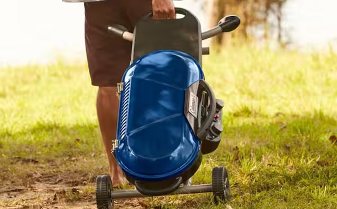 a Person Pulling a Coleman Portable Grill Blue Color