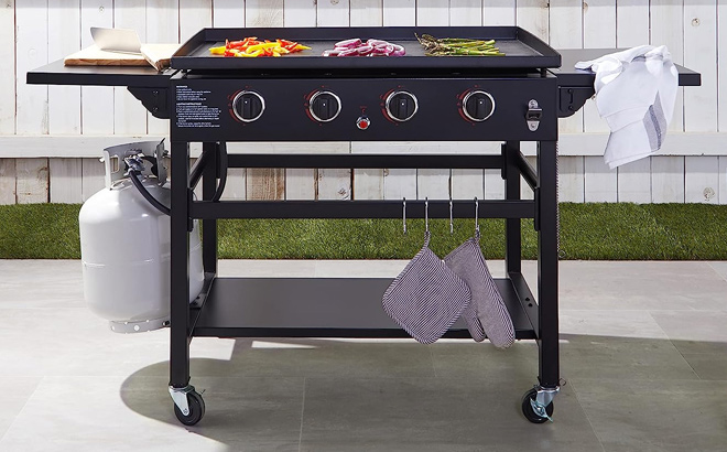 Amazon Basics Outdoor 4 Burner Gas Griddle with 36 Inch Matte Enamel Coated Griddle Top and Side Shelfs in a Backyard