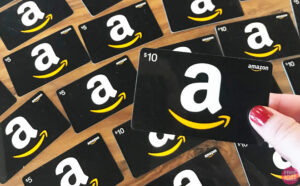 A Person Holding an Amazon Gift Card in front of a Table with More Amazon Gift Cards