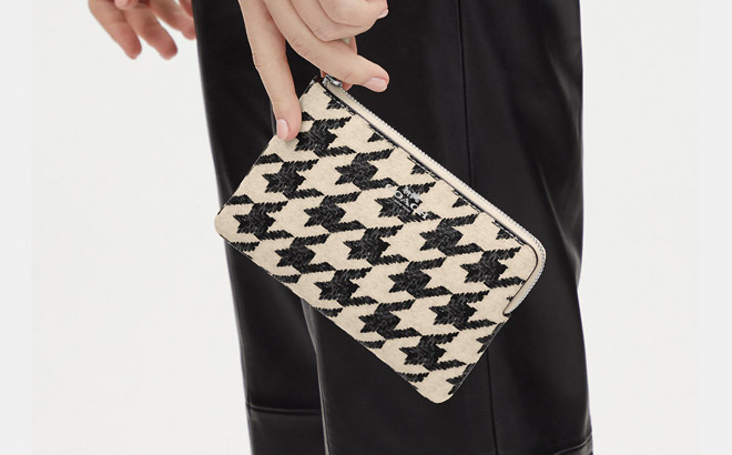 Hand Carrying a Coach Corner Zip Wristlet With Houndstooth Print