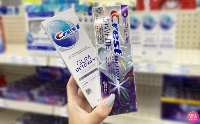 Hand Holding Crest 3D White Brilliance Toothpaste and Crest Gum Detoxify Toothpaste