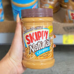 Hand Holding Skippy Peanut Butter Spread Natural Creamy