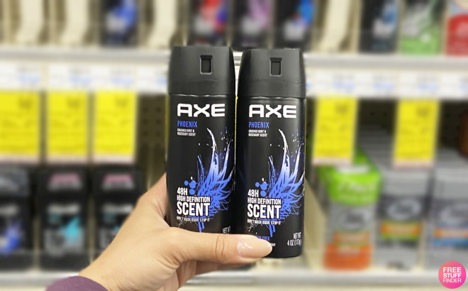 Hand Holding Two Bottles of Axe Mens Body Spray Deodorant
