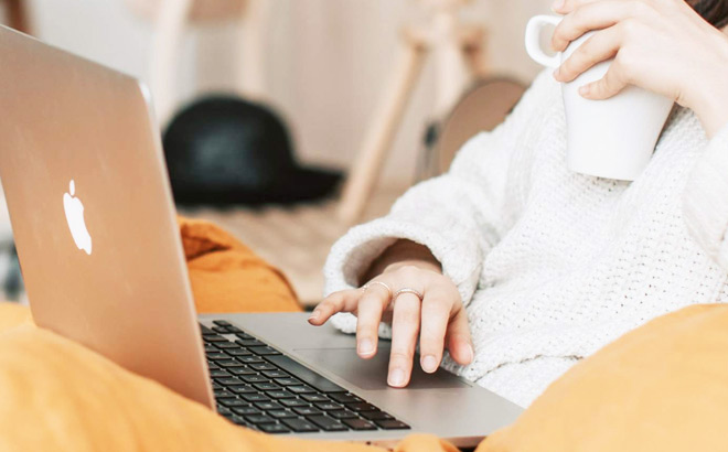 A Person Working on a Laptop and Holding a Cup of Coffee