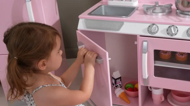 Girl Opening the Storage are of the KidKraft Retro Play Kitchen Set