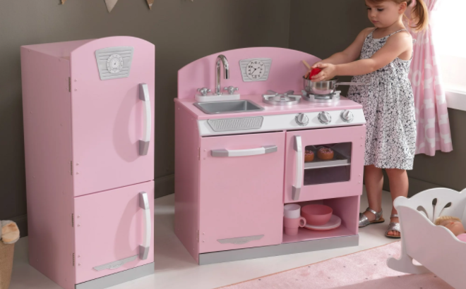 Girl Playing with the KidKraft Pink Retro Wooden Play Kitchen and Refrigerator Play Set