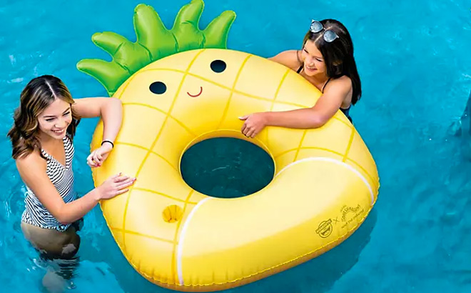 Girls are Holding a BigMouth x Squishmallows Inflatable Ring Pool Pineapple Float in the pool