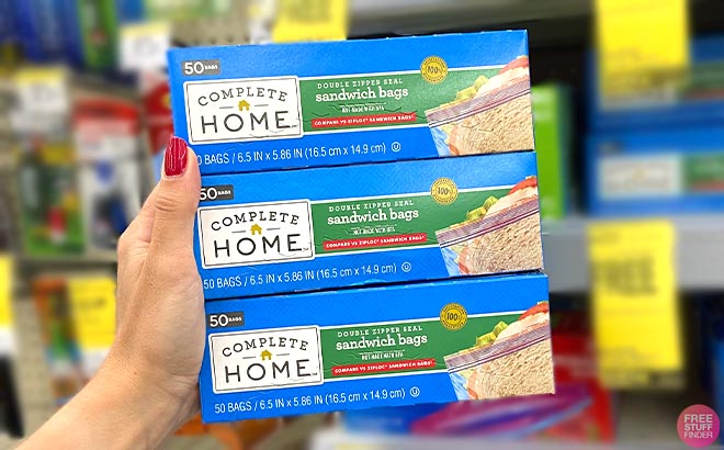 Hand holding three packs of Complete Home Sandwich Bags