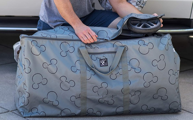 Man Packing a Stroller in J L Childress Disney Baby Stroller Travel Bag