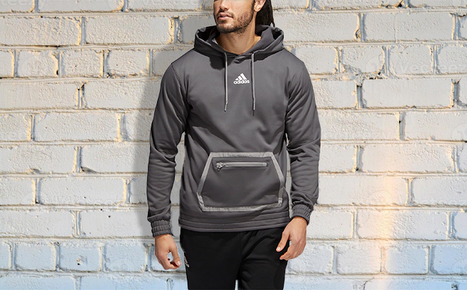 Man Wearing Mens Team Issue Pullover Hoodie in front of Brick Wall 2