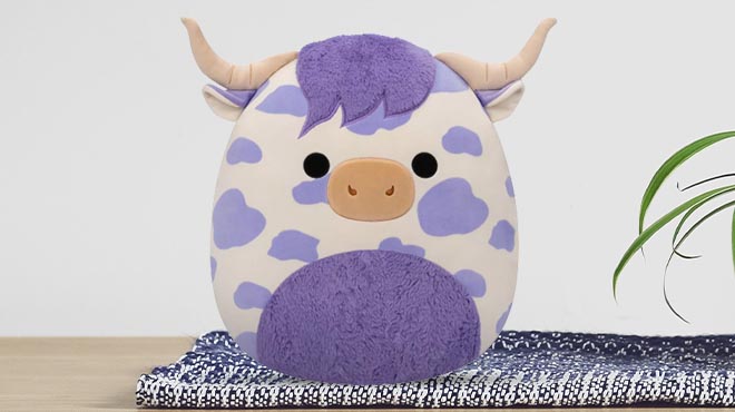 Squishmallows Conway the Purple Spotted Highland Cow 16 Inch Plush on table