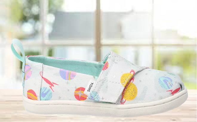 TOMS Foil Cosmic Galaxy Toddler Girls Alpargata Shoes on a Table