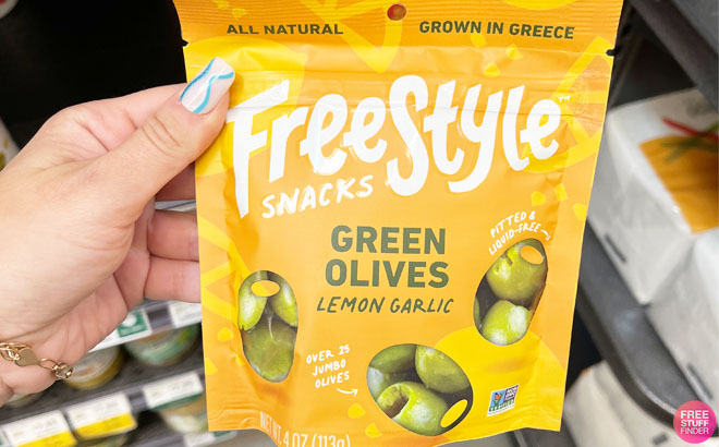 a Hand Holding a Freestyle Snacks Natural Greek Olive Snacks Green Olives Lemon Garlic Flavor