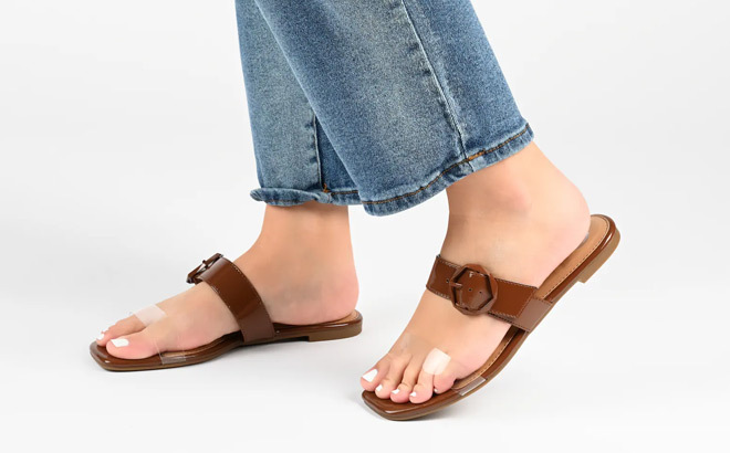 A Woman is Wearing a Journee Collection Jeysha Sandals in Dark Brown Color