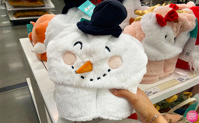 A Hand Holding Up the Snowman Pillowfort Christmas Blanket in Target