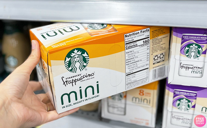 A Hand Holding a Box of Starbucks Mini Frappuccino 8 Pack in Caramel Flavor on a Shelf