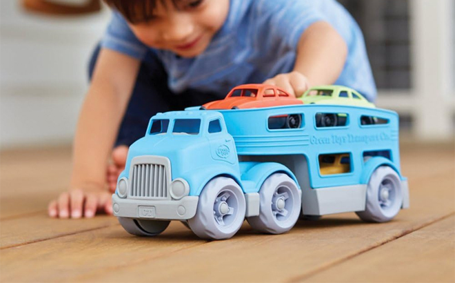 Child Playing with Green Toys Car Carrier in Blue
