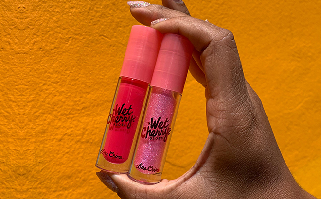 Hand Holding Two Lime Crime Wet Cherry Lip Glosses