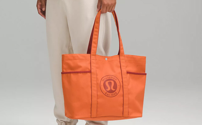 Man is Holding a Lululemon Canvas Tote Bag in Terra Orange Color